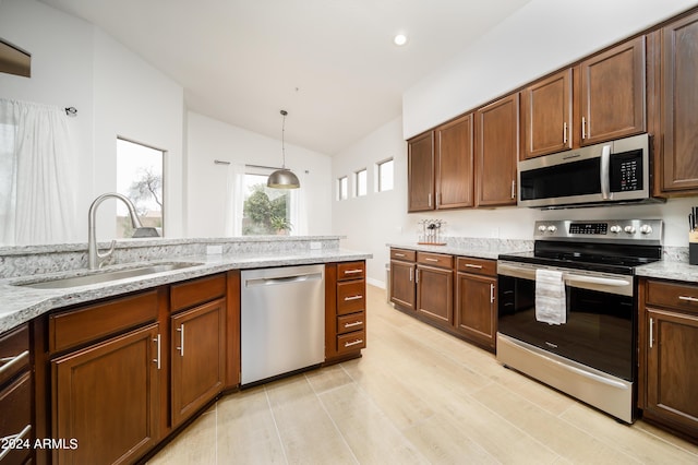 kitchen featuring light stone counters, appliances with stainless steel finishes, sink, and pendant lighting