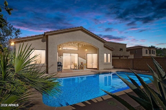 pool at dusk featuring a patio area