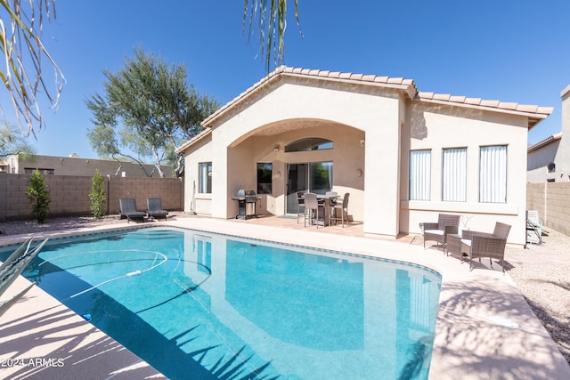 rear view of property with a fenced in pool and a patio