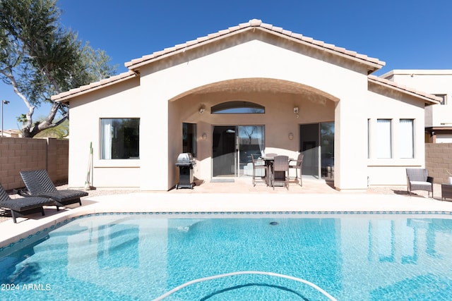 rear view of property with a fenced in pool and a patio area