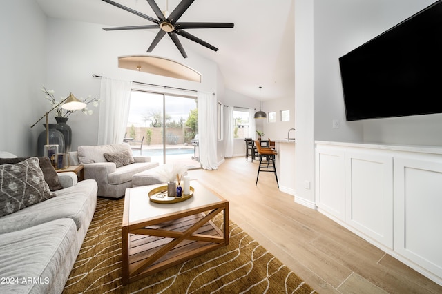 living room with ceiling fan, high vaulted ceiling, and light hardwood / wood-style floors