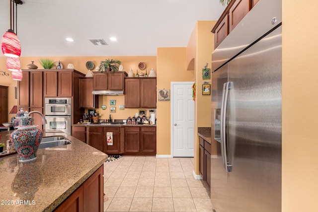 kitchen with under cabinet range hood, a sink, visible vents, appliances with stainless steel finishes, and dark stone counters