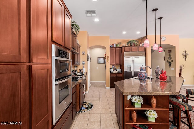 kitchen with arched walkways, a sink, visible vents, appliances with stainless steel finishes, and open shelves