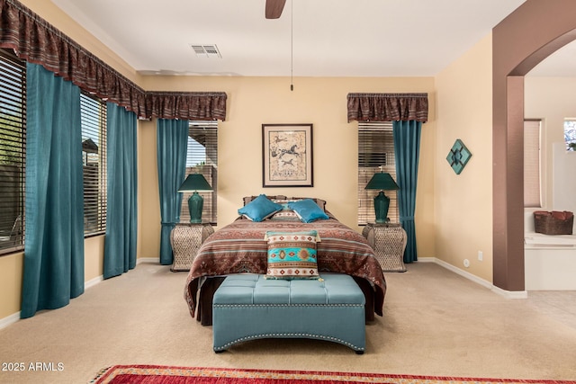 carpeted bedroom featuring arched walkways, a ceiling fan, visible vents, and baseboards