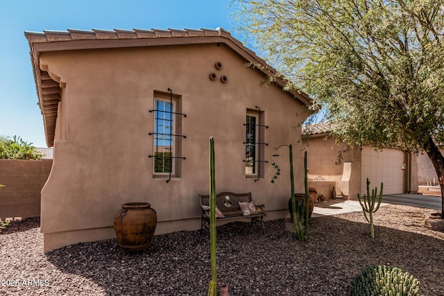 view of home's exterior with an attached garage, driveway, and stucco siding