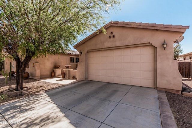 view of front of property featuring an attached garage, fence, concrete driveway, a tiled roof, and stucco siding