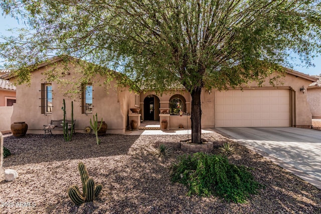 view of front of property featuring an attached garage, a tile roof, concrete driveway, and stucco siding