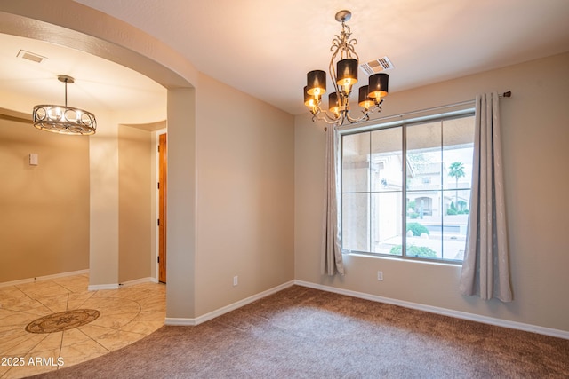 empty room with visible vents, baseboards, carpet flooring, an inviting chandelier, and arched walkways