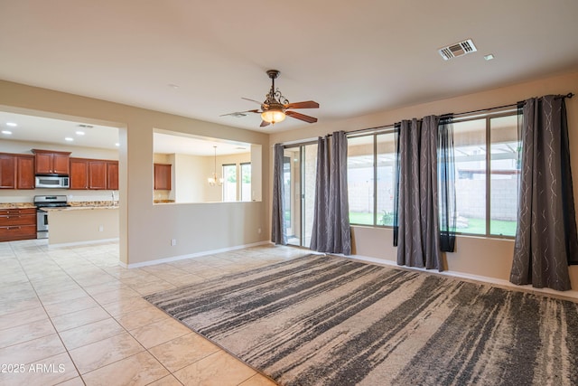 spare room featuring a wealth of natural light, visible vents, ceiling fan with notable chandelier, and baseboards