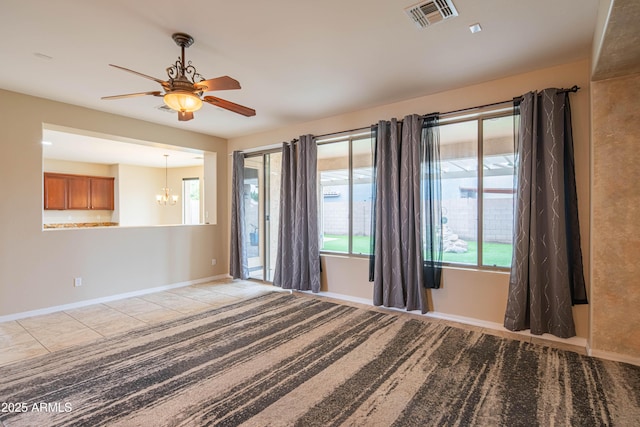 empty room featuring tile patterned flooring, visible vents, ceiling fan with notable chandelier, and baseboards