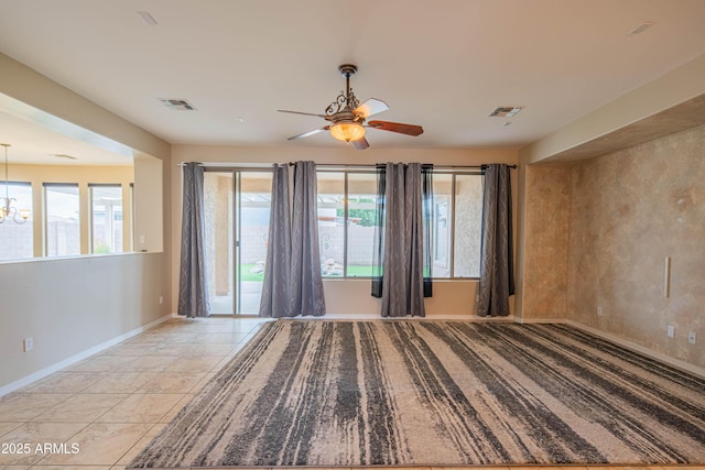 empty room with visible vents, plenty of natural light, baseboards, and ceiling fan with notable chandelier