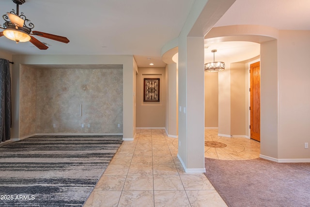 hall featuring arched walkways, baseboards, marble finish floor, and a chandelier