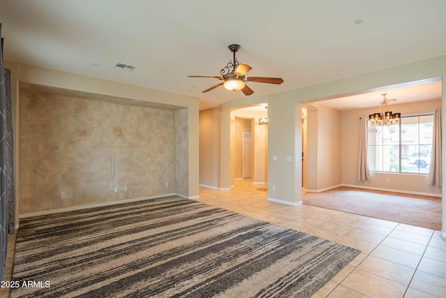 unfurnished room featuring visible vents, baseboards, light tile patterned floors, ceiling fan with notable chandelier, and arched walkways