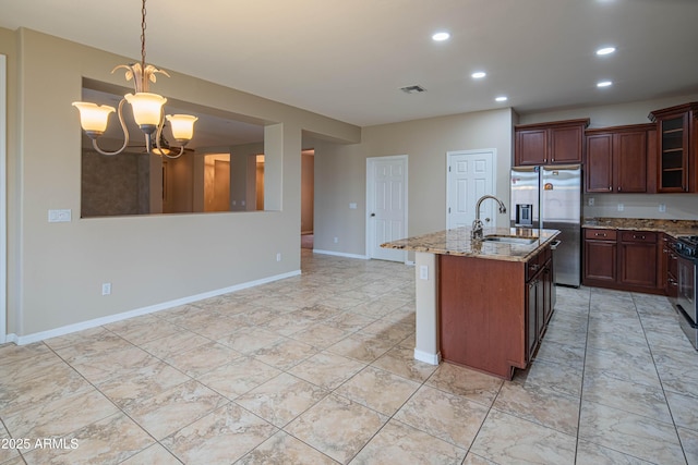 kitchen featuring visible vents, a notable chandelier, light stone counters, a sink, and appliances with stainless steel finishes