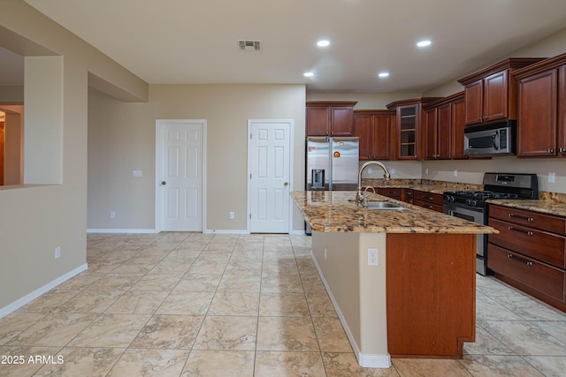 kitchen with visible vents, a sink, light stone counters, stainless steel appliances, and glass insert cabinets