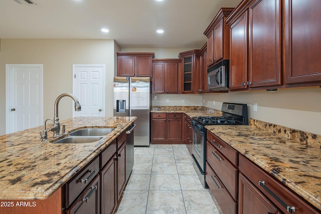 kitchen with a sink, light stone counters, recessed lighting, stainless steel appliances, and glass insert cabinets