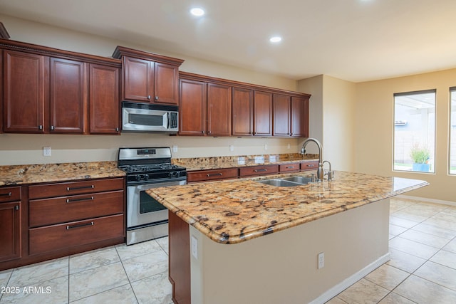 kitchen featuring a sink, light stone countertops, a center island with sink, and stainless steel appliances