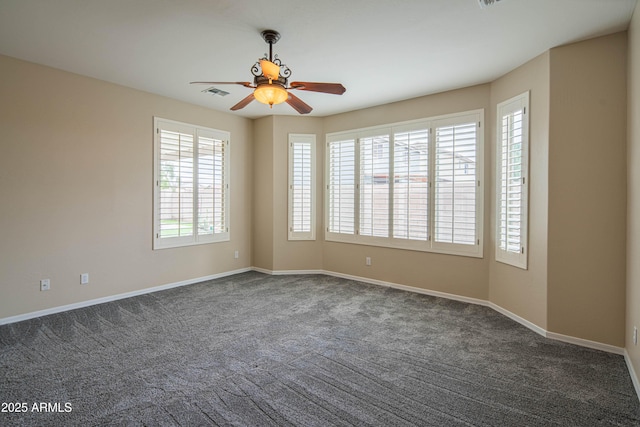 spare room featuring baseboards, visible vents, dark carpet, and ceiling fan