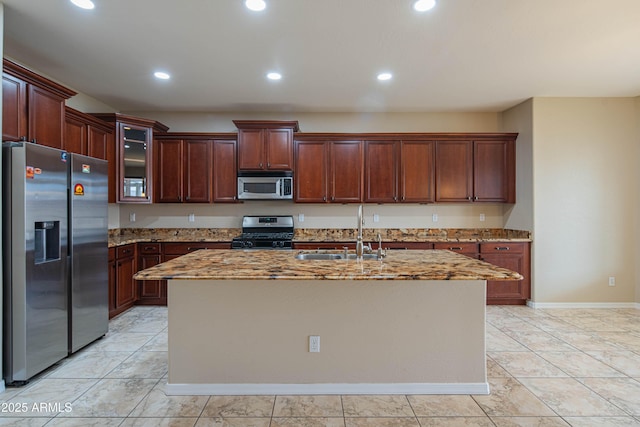 kitchen with an island with sink, light stone counters, recessed lighting, appliances with stainless steel finishes, and a sink