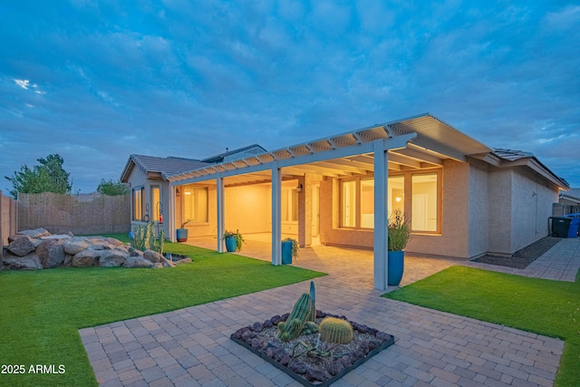 back of property featuring stucco siding, a lawn, a patio, fence, and a tiled roof