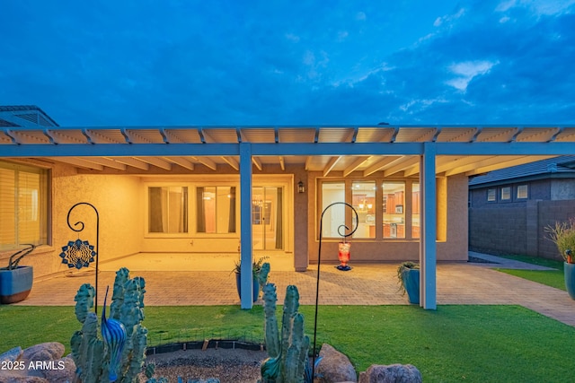 exterior space with stucco siding, a patio, a lawn, and fence