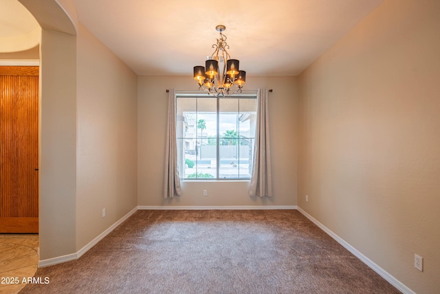 empty room featuring an inviting chandelier, carpet flooring, and baseboards