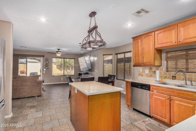 kitchen featuring sink, decorative light fixtures, a center island, dishwasher, and backsplash