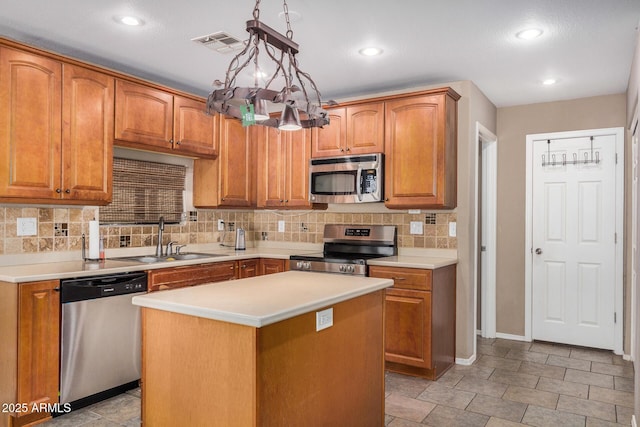 kitchen with sink, decorative light fixtures, a kitchen island, stainless steel appliances, and decorative backsplash