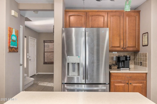 kitchen featuring stainless steel refrigerator with ice dispenser, light tile patterned floors, and decorative backsplash