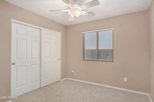 unfurnished bedroom featuring light colored carpet, ceiling fan, and a closet