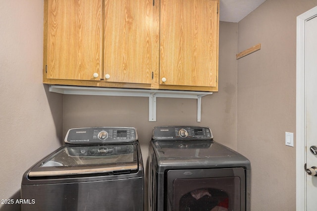 laundry area with separate washer and dryer and cabinets