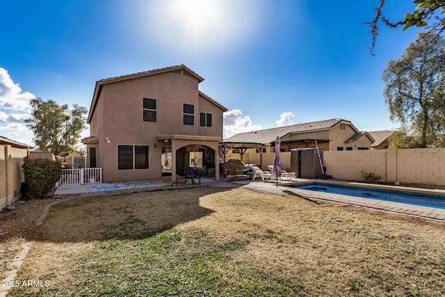 back of property with a fenced in pool, a lawn, and a patio area