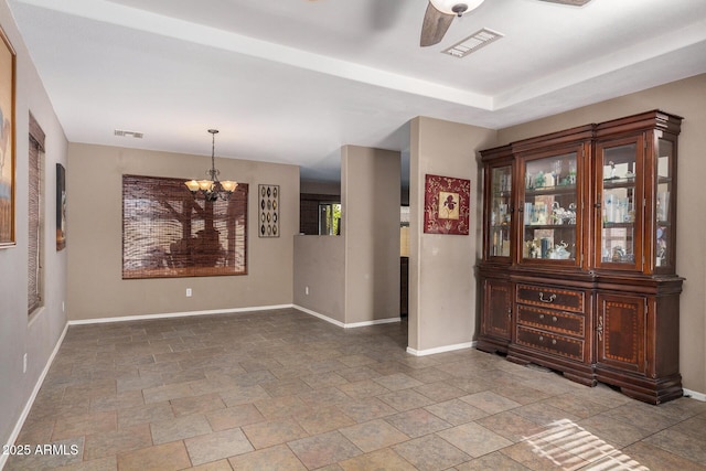 unfurnished dining area with ceiling fan with notable chandelier and a tray ceiling