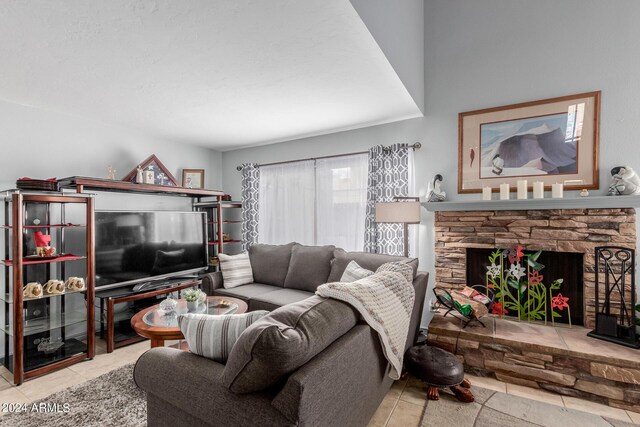 living room featuring a stone fireplace and light tile patterned floors