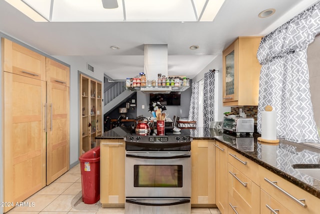 kitchen with light brown cabinets, dark stone counters, light tile patterned flooring, and range with electric cooktop