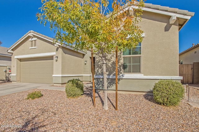 view of front of home with stucco siding, concrete driveway, a garage, and fence