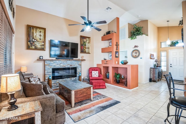 living room featuring a fireplace, vaulted ceiling, ceiling fan, and light tile patterned flooring