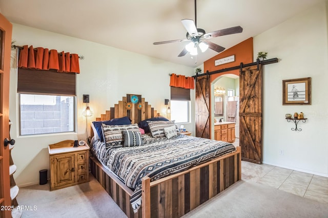 bedroom with ceiling fan, light tile patterned floors, a barn door, connected bathroom, and lofted ceiling