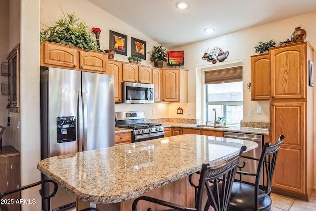 kitchen featuring sink, lofted ceiling, a kitchen bar, a kitchen island, and appliances with stainless steel finishes