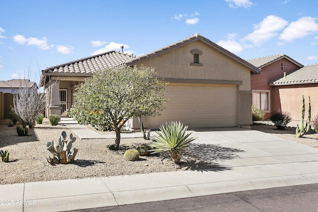 view of front of house with a tile roof, an attached garage, driveway, and stucco siding