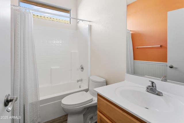 full bathroom with shower / bathtub combination with curtain, toilet, a wainscoted wall, and vanity