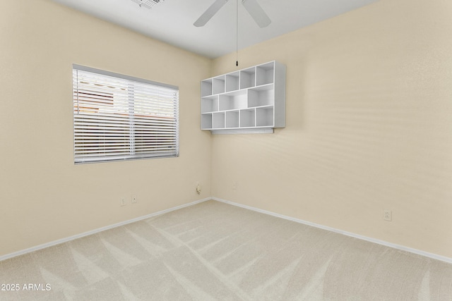 spare room featuring light colored carpet, baseboards, and ceiling fan