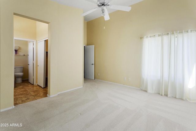 unfurnished bedroom with connected bathroom, baseboards, a towering ceiling, and light carpet