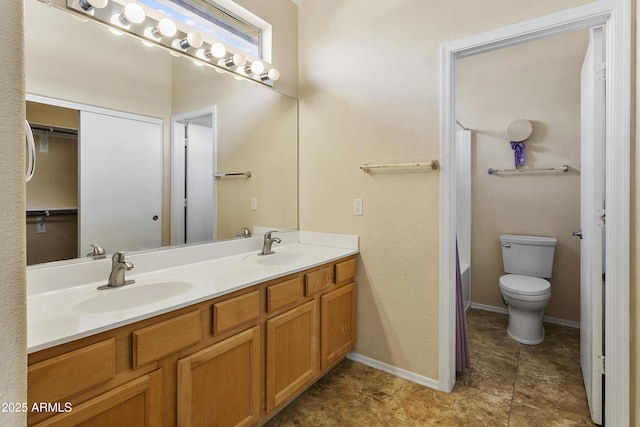 full bathroom featuring a sink, baseboards, toilet, and double vanity