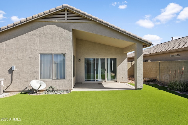 back of property with a patio area, stucco siding, a lawn, and fence