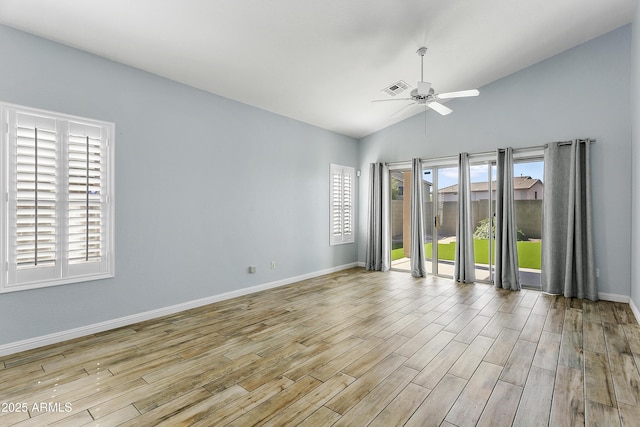 empty room with visible vents, plenty of natural light, wood finished floors, and vaulted ceiling