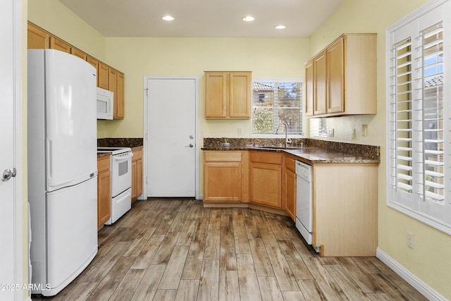 kitchen featuring light brown cabinets, light wood-type flooring, recessed lighting, white appliances, and a sink