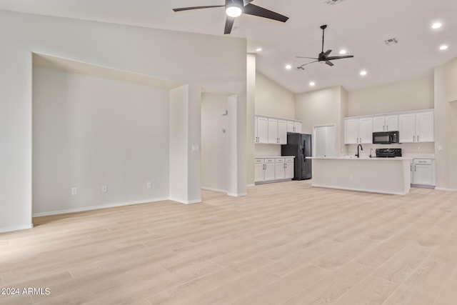 kitchen featuring a center island with sink, black appliances, light hardwood / wood-style floors, high vaulted ceiling, and ceiling fan