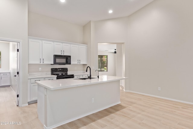 kitchen with a center island with sink, black appliances, sink, and white cabinetry