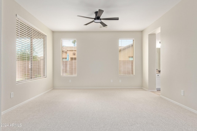 carpeted spare room featuring plenty of natural light and ceiling fan